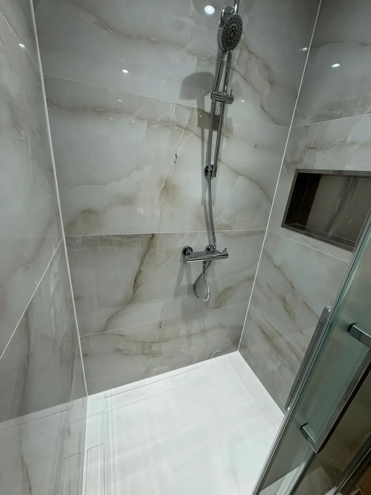 Douche met tegels in onyxlook, chromen douchekraan en een inbouwnis