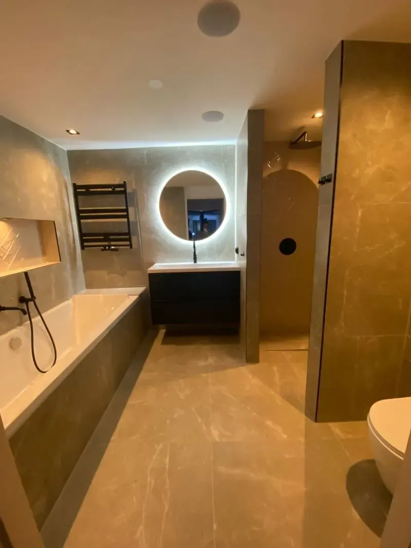 Badkamer met ligbad, verlichte nis en ronde spiegel