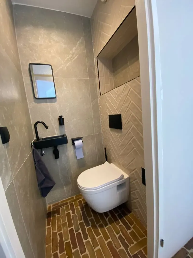 Toilet met visgraatwand, nis en zwart fonteintje