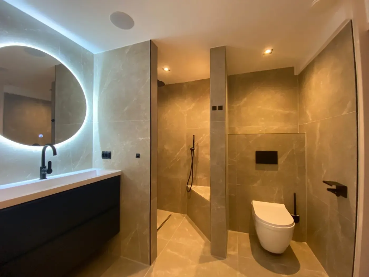 Badkamer in warme steenlook met ovale ledspiegel