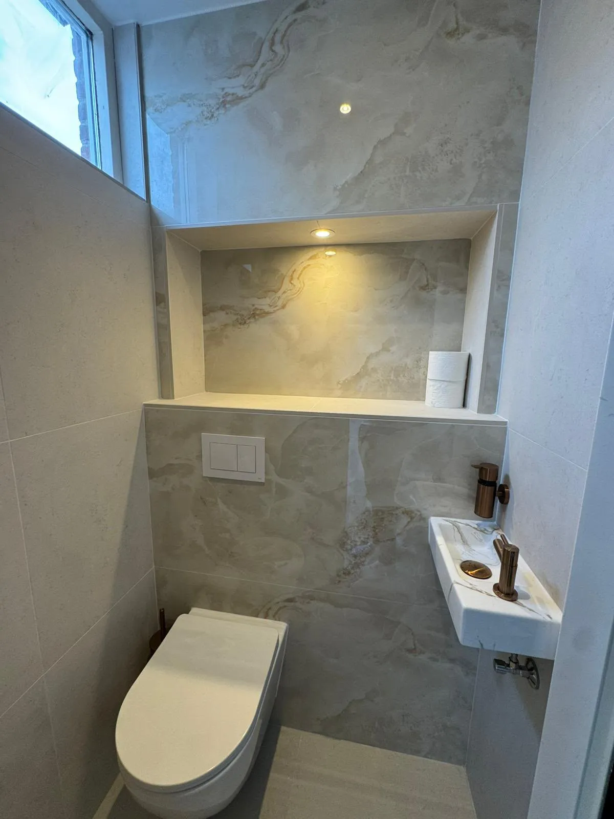 Toilet met verlichte nis, koperen kraan en fontein in marmerlook